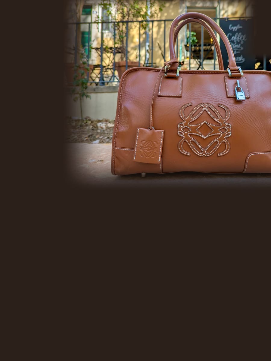 A tan Loewe Amazona bag on a stone step outside a Lisbon café